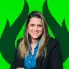 Mulher sorridente usando blazer preto e camisa azul, com fundo verde estilizado, transmitindo energia e profissionalismo.