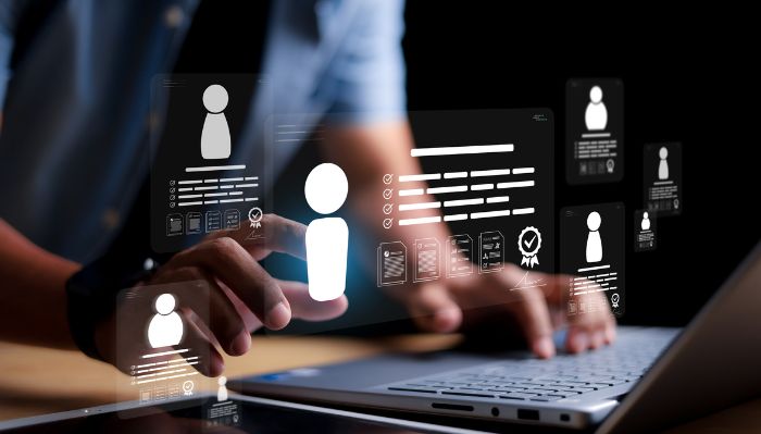 Pessoa usando um laptop enquanto interage com ícones flutuantes de perfil, documentos e certificações, simbolizando o gerenciamento de identidades e informações de usuários.