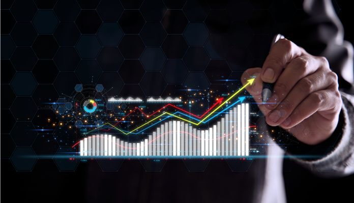 Mão segurando uma caneta enquanto desenha um gráfico de barras com linhas ascendentes, representando crescimento, tendências de mercado e análise de dados em um cenário tecnológico.